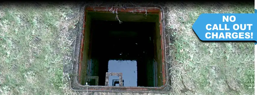 A manhole cover opened, revealing a completely blocked drain that needs assistance