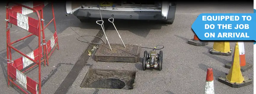 The CCTV drain crawler is ready to go down the drain, with safety fences in place, and a service van visible in the background