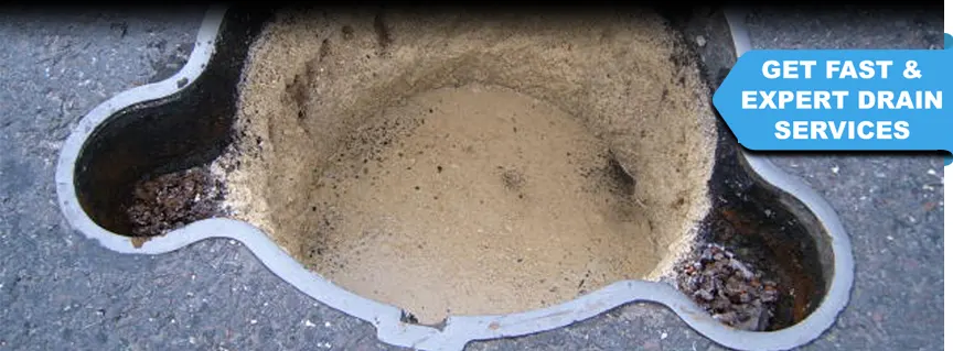 A manhole cover opened, revealing a completely blocked drain filled with fat and grease from a restaurant in West Sussex, requiring urgent drain cleaning